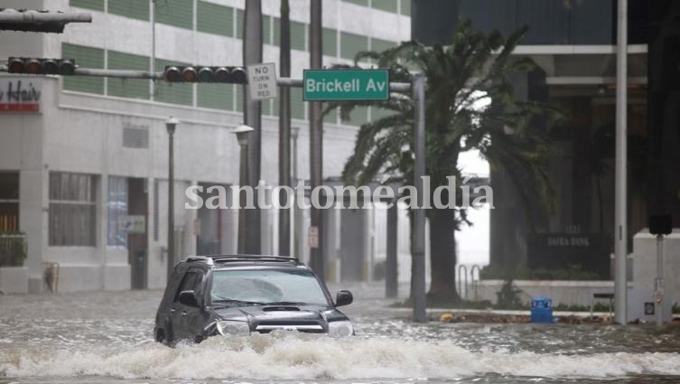 Un auto transita por una avenida de Miami inundada.