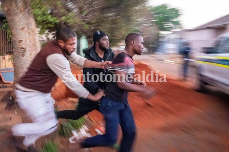 Dos nigerianos agarran a un hombre que estaba saqueando su tienda en el barrio de Troyville, en Johannesburgo, y lo llevan a la policía. (Foto: AP)