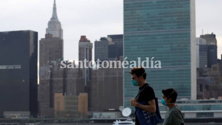 Personas con mascarilla caminan frente al horizonte de Manhattan a lo largo de la costa de Long Island City. (Foto: RT)