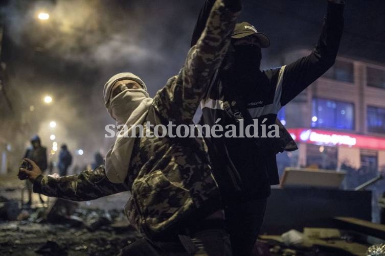 Un hombre con máscara y capucha arroja piedras a la policía durante protestas en Bogotá. (AP)