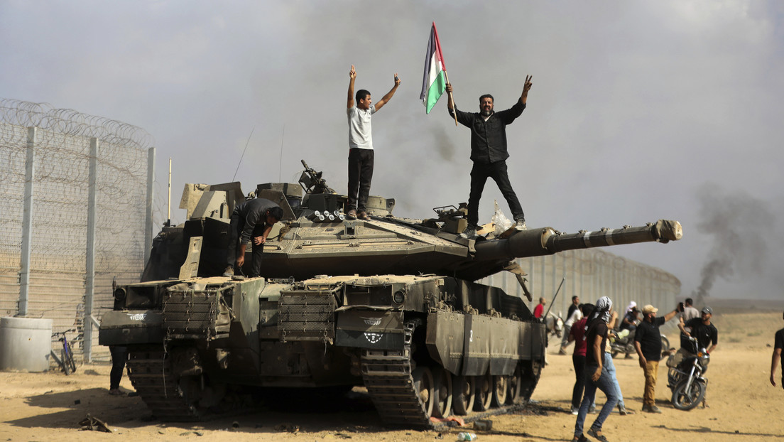 Palestinos ondean su bandera y celebran junto a un tanque israelí destruido en la valla de la Franja de Gaza, el 7 de octubre de 2023. (Foto: Yousef Masoud / AP)