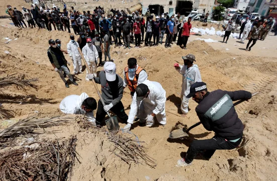 Varias personas trabajan para trasladar a un cementerio los cuerpos de los palestinos muertos durante la ofensiva militar israelí y enterrados en el hospital Nasser. (Foto: Reuters / Ramadan Abed)