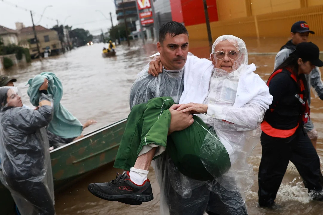 Un voluntario lleva a un hombre, que ha sido evacuado de una zona inundada en Porto Alegre. (Foto: NA)