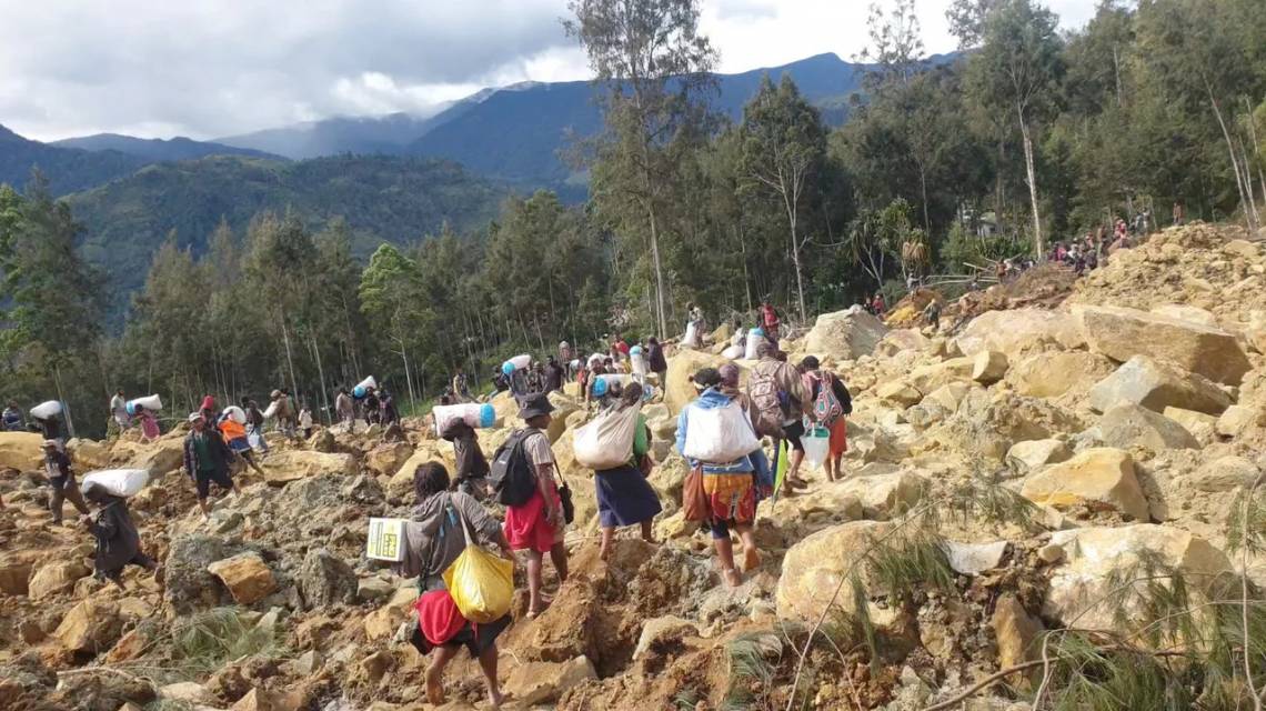 Varias personas cargan bolsas tras un corrimiento de tierras en la provincia de Enga, Papúa Nueva Guinea. (Foto: Reuters)